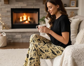 May include: A person wearing a black short-sleeve shirt and pajama pants. The pajama pants are yellow with a black pattern. The person is sitting on a white couch and holding a white mug. A fireplace is in the background.