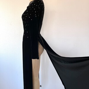 May include: A black velvet gown with a long train and beaded embellishments on the bodice.