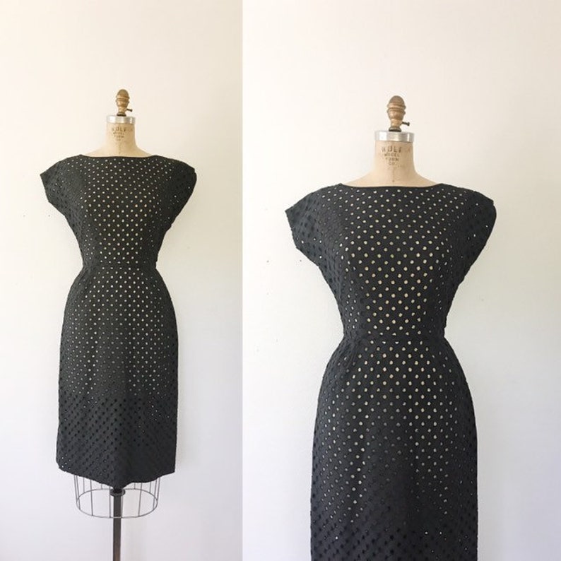 May include: A black sleeveless dress with a polka dot pattern. The dress is made of a lightweight fabric and has a fitted silhouette.