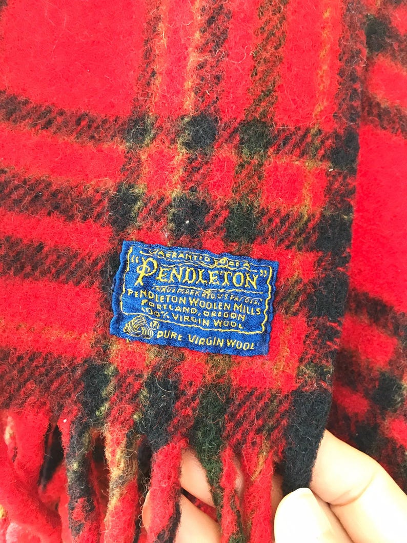 May include: Red and black plaid Pendleton wool blanket with fringe. The label reads "Pendleton Woolen Mills, Portland, Oregon, 100% Virgin Wool, Pure Virgin Wool."