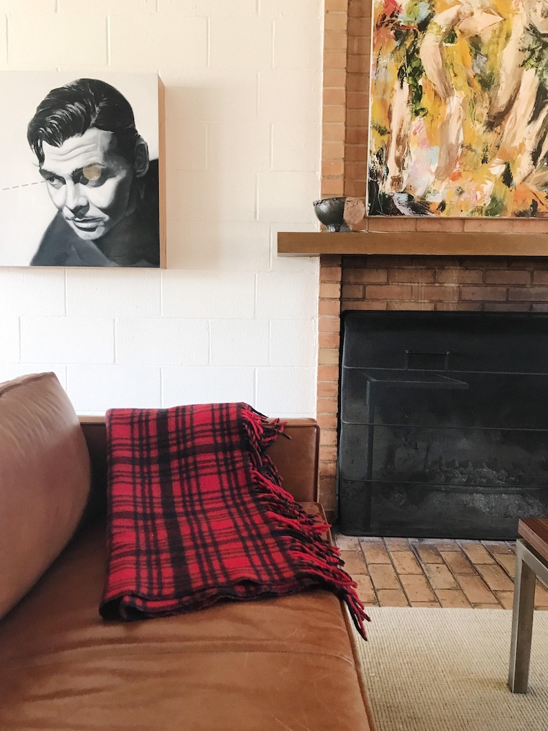 May include: A red and black plaid throw blanket with fringe on a brown leather couch in front of a brick fireplace.