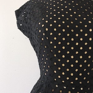 May include: Black dress with a polka dot pattern. The dress is made of a lightweight, breathable fabric and has a fitted silhouette.