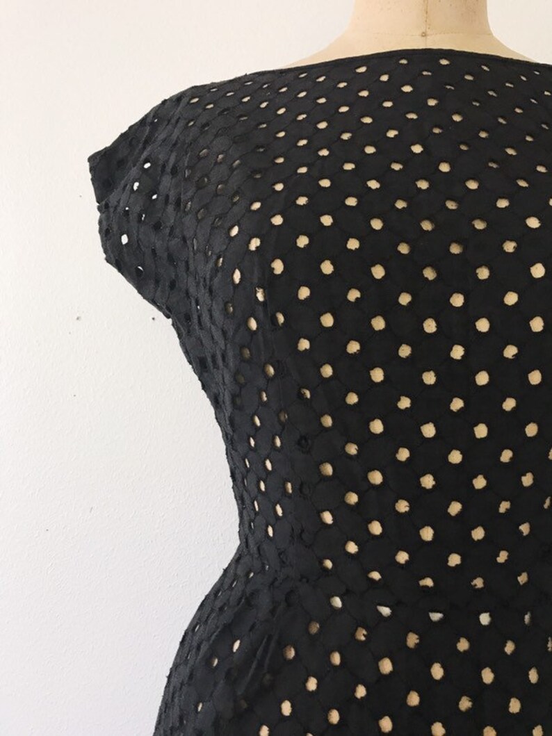 May include: Black dress with a polka dot pattern. The dress is made of a lightweight, breathable fabric and has a fitted silhouette.