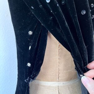 May include: Black velvet dress with sequins. The dress has a low back and is fitted.