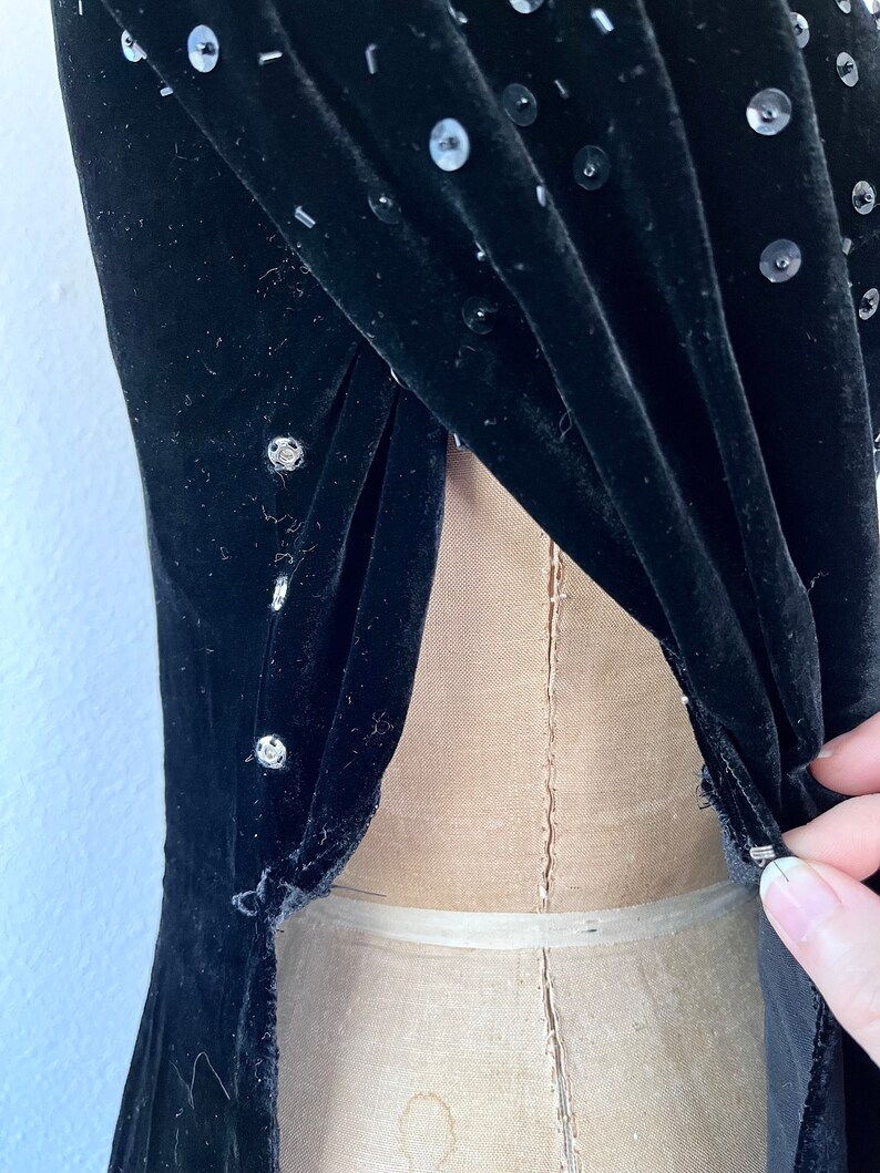 May include: Black velvet dress with sequins. The dress has a low back and is fitted.