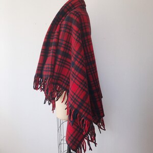 May include: Red and black plaid wool shawl with fringe trim. The shawl is draped over a mannequin.