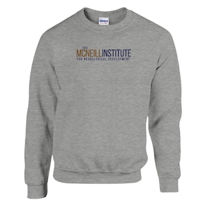 Op de afbeelding: Een grijs sweatshirt met de tekst "THE MCNEILL INSTITUTE FOR NEUROLOGICAL DEVELOPMENT" gedrukt op de voorkant in goud en blauw.