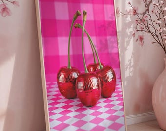 Peut inclure: Une impression encadrée de quatre cerises rouges brillantes avec des tiges vertes sur un fond à carreaux roses. L'impression est posée contre un mur orné de motifs floraux roses. Un vase rose contient des branches fleuries.