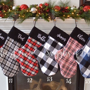 May include: Six personalized Christmas stockings with black felt cuffs and plaid fabric. The stockings are hung on a fireplace mantel with a garland of greenery and red ornaments. The names on the stockings are Mom, Dad, Bella, James, Olivia, and Noah.