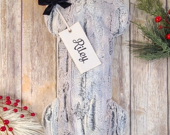 May include: A gray plush dog bone stocking with a black velvet bow and a white tag that says "Riley".