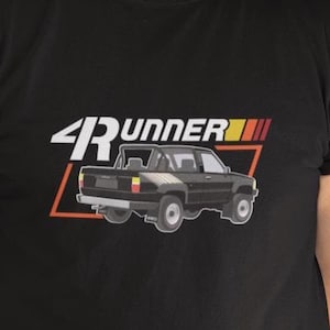 May include: A black t-shirt with a graphic of a black pickup truck and the text "4RUNNER" in red, yellow, and white.