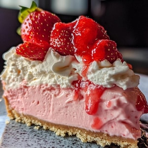 Peut inclure: Une part de cheesecake à la fraise avec une croûte de biscuits graham, garnie de crème fouettée et de fraises fraîches.