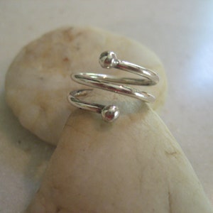 May include: A silver ring with a spiral design and two small round beads.