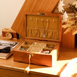 May include: A wooden jewelry box with a lock and key. The box has a velvet interior and multiple compartments for storing jewelry. The box is open and there are several pieces of jewelry inside, including necklaces, earrings, and rings.