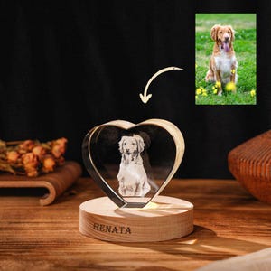 Op de afbeelding: Een hartvormige kristallen foto met een afbeelding van een hond, gemonteerd op een houten voet met de inscriptie "RENATA". Een aparte foto van de hond is zichtbaar. Het kristal is helder en de voet is lichtbruin.