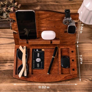 May include: A wooden desk organizer, 11.02 inches wide and 9.06 inches tall, with compartments for a phone, sunglasses, a credit card, pen, and other accessories. The organizer is stained a dark brown color and includes a watch and smart watch holder.