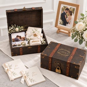 May include: A dark brown wooden keepsake chest with metal latches and a combination padlock. The chest features the text William & Mia May 24, 2024. Inside are wedding photographs, two cream-colored vow booklets tied with ribbons, and two gold rings.