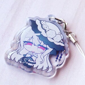 May include: A clear acrylic charm featuring a stylized anime character with long white hair, wearing a white hat adorned with roses and a dark blue brim. The character has pink eyes and a white outfit with dark blue accents, attached to a silver clasp.