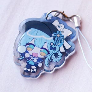 May include: A clear acrylic charm featuring a chibi-style character with light blue hair, wearing a dark blue hat and outfit with white accents. The character has large teal eyes and is holding a small white object. A silver lobster clasp is attached.