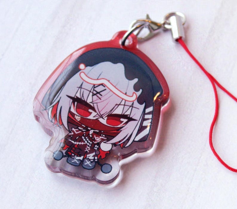 May include: A clear acrylic charm featuring a stylized anime character with white hair, red eyes, and a red mask. The character wears a dark hooded outfit with red accents and stitching details. A silver metal lobster clasp and a red cord are attached.