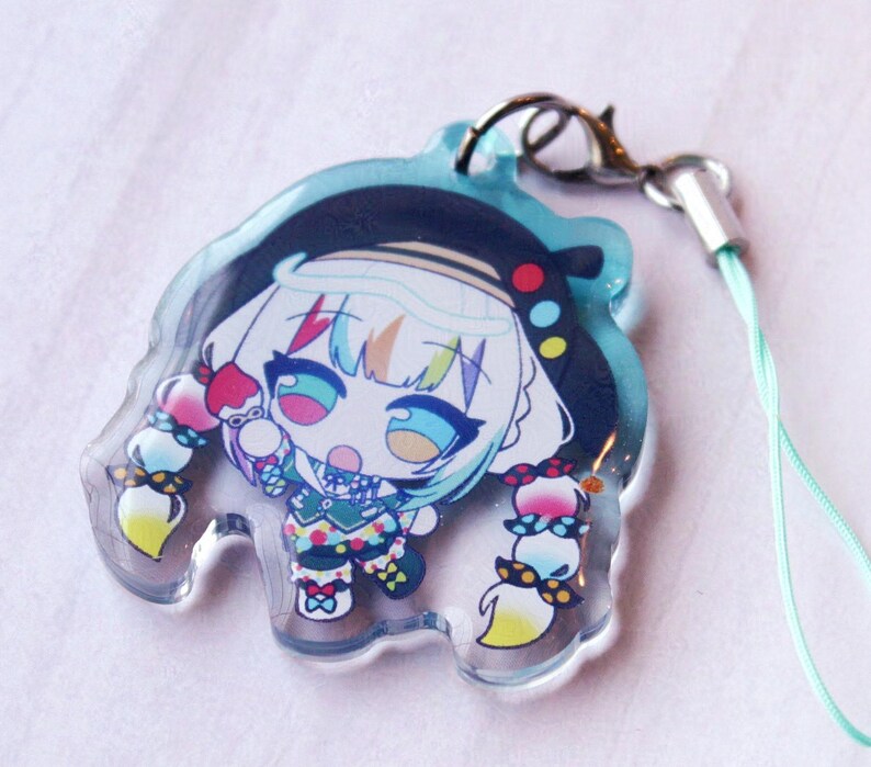 May include: A clear acrylic charm featuring a colorful anime-style character with white hair, a black beret, and multi-colored clothing. The character has large blue eyes and braided hair with red, yellow, and blue accents. Includes a silver lobster clasp.