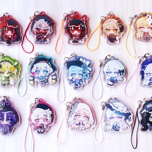 May include: A collection of fifteen acrylic charms featuring diverse anime-style character illustrations. Each charm is attached to a colorful looped cord and displays a unique chibi-style figure with distinct hair colors, outfits, and accessories.