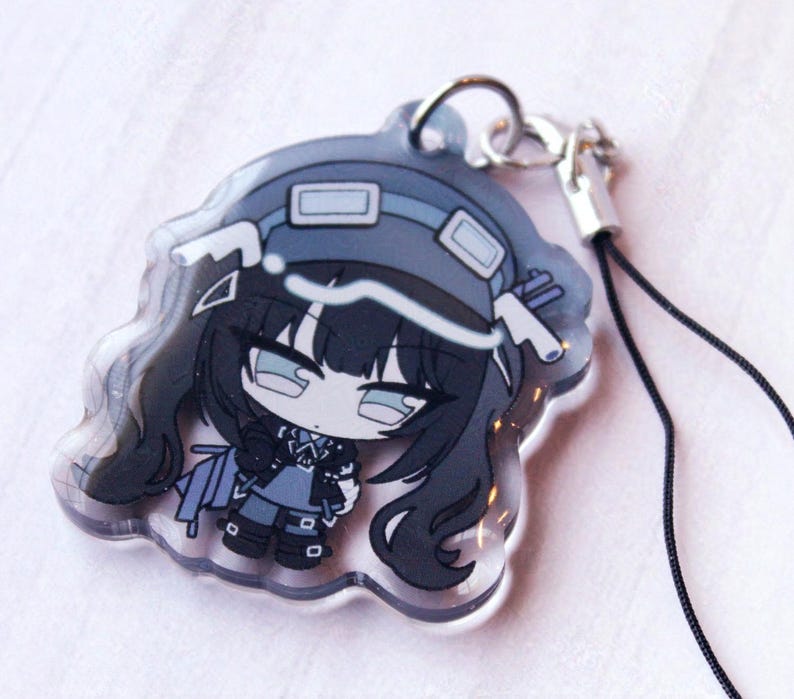 May include: A clear acrylic charm featuring a stylized anime-inspired character with long black hair, wearing a dark blue hat with goggles, a matching outfit, and boots. The charm includes a silver metal jump ring and a thin black cord attachment.