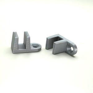 May include: Two silver-colored plastic door stops. One door stop has a single hole, while the other has two holes.