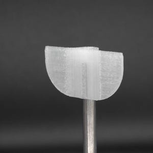 May include: A white plastic 3D printed object with a curved shape. The object is attached to a metal rod.