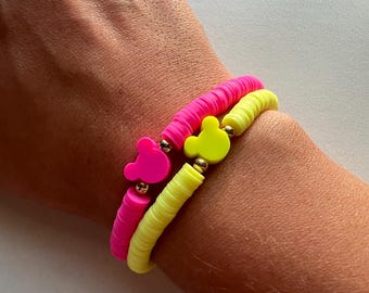 May include: Two neon bracelets with Mickey Mouse charms. The top bracelet is yellow and the bottom bracelet is pink.