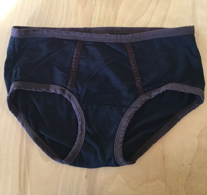 K&ouml;nnte beinhalten: Schwarze Unterw&auml;sche mit braunem Besatz und Spitzendetails.