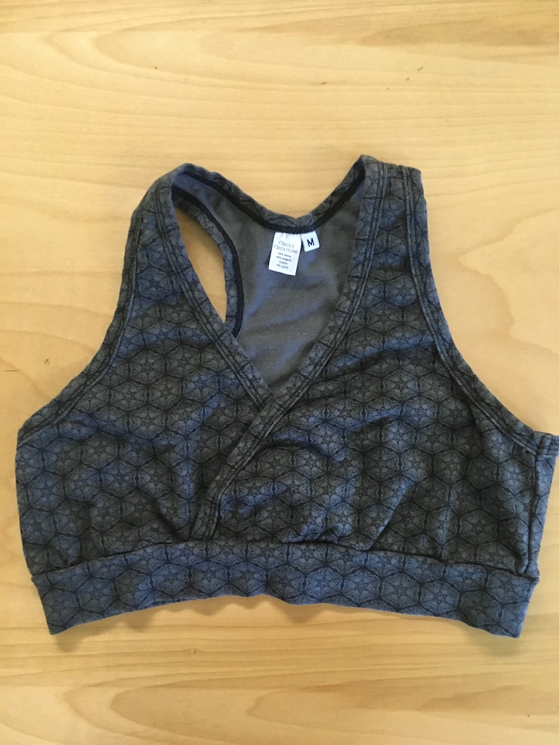 May include: A grey sports bra with a geometric pattern. The bra has a racerback style and a v-neck. The tag says "Only Hearts" and "M".