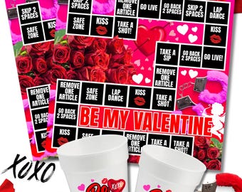 May include: Valentine's Day game board and cup stickers. The game board features squares with phrases like "Kiss" and "Take a Shot!" Two white cups are printed with "Be Mine" and lip graphics. Red rose petals and a pair of handcuffs are also visible.
