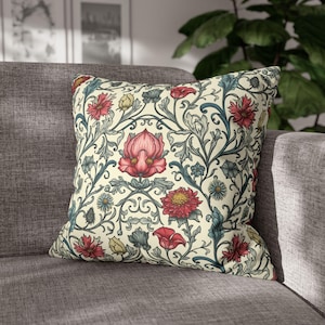 May include: A cream-coloured throw pillow with a floral pattern featuring red, pink, and blue flowers on a leafy vine design.
