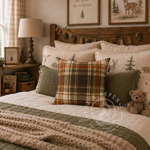 May include: A square throw pillow featuring a plaid pattern in shades of orange, green, and cream, centered on a bed layered with olive green textured pillows, a cream quilted coverlet, and a chunky knit throw blanket in a neutral beige tone.