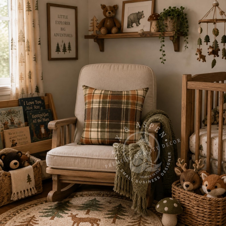May include: A light beige upholstered rocking chair featuring a square plaid pillow in shades of orange, brown, and green. A textured olive green throw blanket with fringe hangs over the armrest, set in a room with woodland-themed decor.