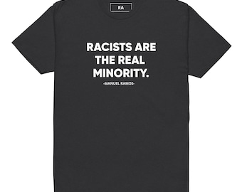May include: Black t-shirt with the text "RACISTS ARE THE REAL MINORITY." below which is the text "-MANUEL RAMOS-". The shirt has a small white tag in the upper center.
