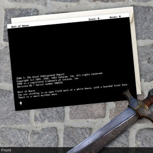 May include: A black and white text-based game screen with the title "The Great Underground Empire" and copyright information. The game text describes a white house with a boarded front door and a small mailbox.