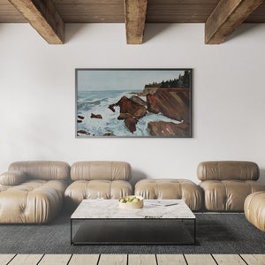 May include: A living room interior with a large framed painting of a seascape with rocky cliffs and crashing waves. The painting is hanging on a white wall above a brown leather sectional sofa. A coffee table with a marble top sits in front of the sofa.