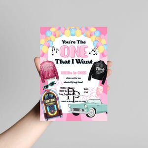 May include: A pink invitation card with the text "You're The ONE That I Want" and "Millie is ONE". The card features illustrations of a pink jacket, a black jacket, a jukebox, sunglasses, a milkshake, and a vintage car.