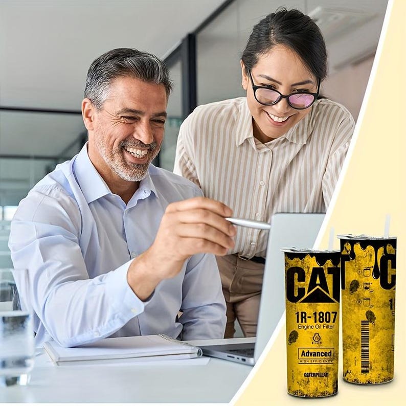Op de afbeelding: Twee cilindrische bekers met het CAT-logo en de tekst "1R-1807 Engine Oil Filter" in zwart en geel. De bekers hebben een verweerd, industrieel ontwerp. Twee mensen lachen en kijken naar een laptop.