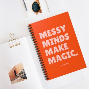 May include: Orange spiral notebook with the text "Messy Minds Make Magic." in pink lettering. The text "Meet the Mess" is printed in smaller letters below the main text.