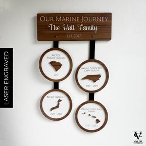 May include: A wooden wall hanging with the text "OUR MARINE JOURNEY" and "The Hall Family". It features four circular plaques with state and country outlines, dates, and locations: MCRD Parris Island, Camp Lejeune, MCAS Iwakuni, and Hawaii.