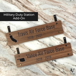 May include: Two wooden plaques with black text. The top plaque reads "Travis Air Force Base 2019-2021" with a California outline. The bottom plaque reads "Vance Air Force Base 2018-2019" with an Oklahoma outline. Both have leather straps.