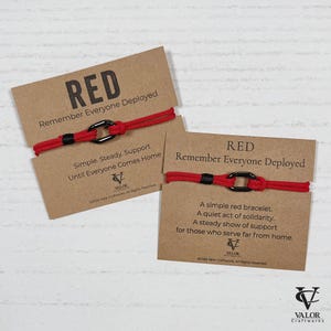 May include: Two red bracelets with black accents and a black clasp are displayed on brown cards. The cards read "RED Remember Everyone Deployed" and include text about support and solidarity.
