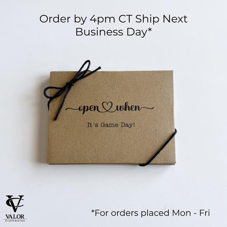 May include: A brown gift box tied with black twine. The box has the words "open when" and "It's Game Day!" printed on the front. The Valor Craftworks logo is in the bottom left corner.
