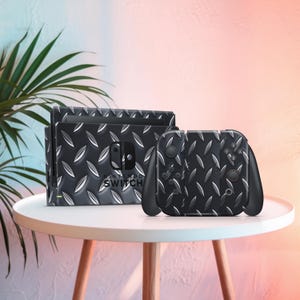 Può includere: Una console Nintendo Switch nera e controller con un motivo a piastra diamantata. La console e i controller sono su un tavolo bianco. Il logo Nintendo Switch è visibile.