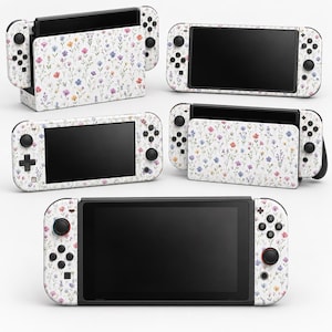Può includere: Una collezione di console di gioco e dispositivi portatili con una skin bianca caratterizzata da un delicato motivo a fiori di campo multicolore. Il set include una base, una console portatile e controller, tutti decorati con piccoli fiori.