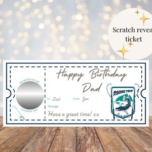 May include: A white scratch-off birthday card with a teal border and text. The card reads "Happy Birthday Dad" and includes a "Fishing Trip" graphic. A silver scratch-off area is on the left.