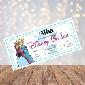 May include: A blue and white ticket for a Disney On Ice show featuring a cartoon image of Elsa and Anna from Frozen. The ticket is for Alba and says "You're heading to watch Disney On Ice" with the date "15th December" and the venue "Manchester Arena". The message on the ticket says "Happy birthday! Love mum & dad x".